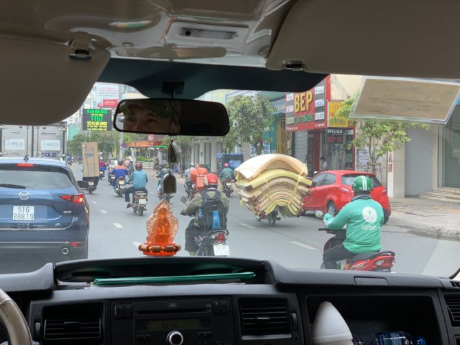 A good illustration of motorbike craziness. Note the mattresses but also the guy with the fridge! Another man drove carrying a tray of food in one hand.